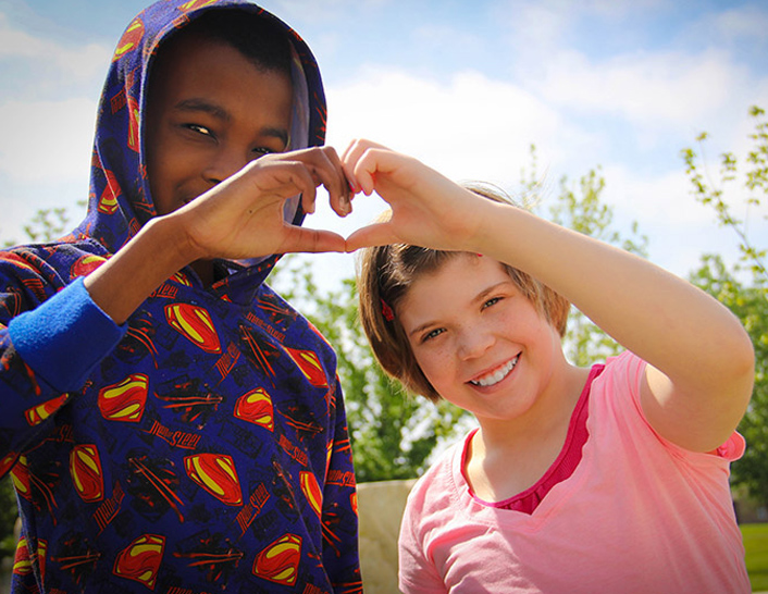 two kids making a heart with hands